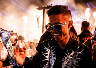 Two festival-goers wearing sunglasses enjoy the vibrant atmosphere of a music festival.