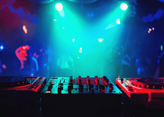 A DJ booth with equipment surrounded by colorful lights in a lively nightclub, enhancing the EDM experience.